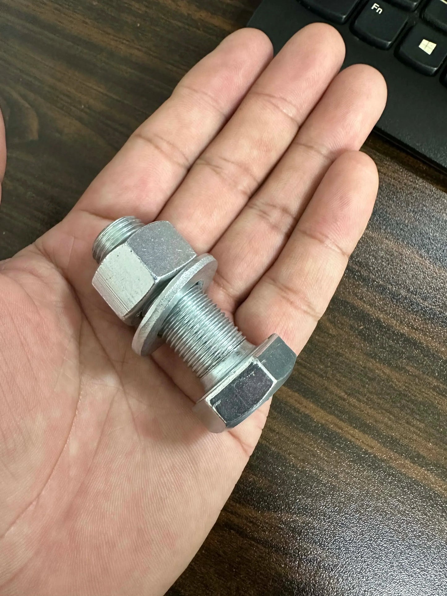 Metal screw bolt stash safe with hidden compartment for cash or pills, held in hand.