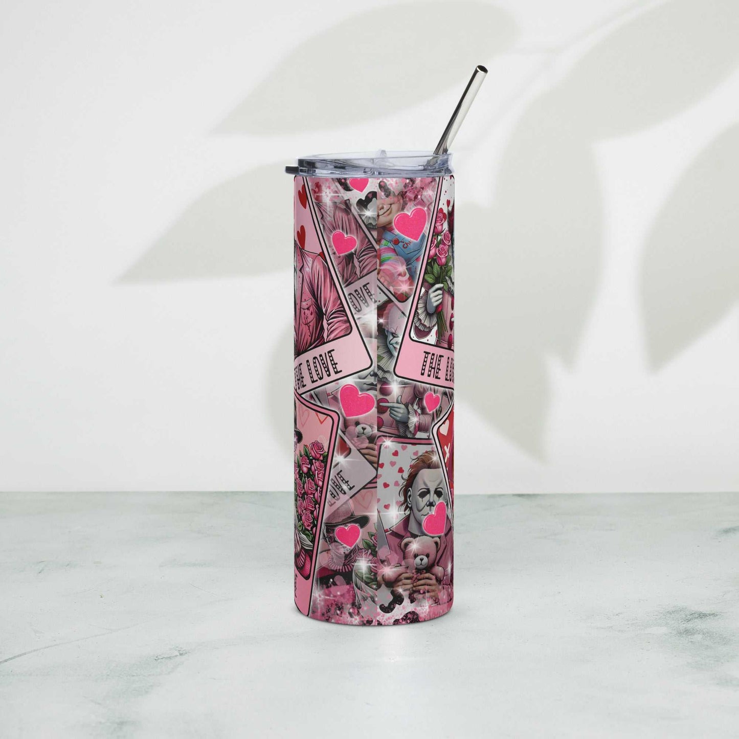 Stainless steel tumbler with colorful design and metal straw on a light background.