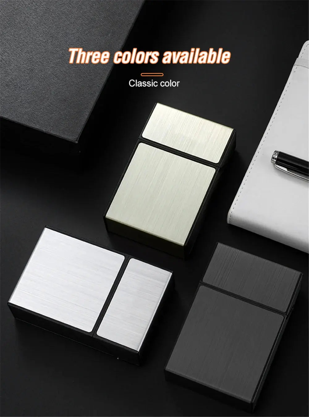 Three metal portable cigarette cases in gold, silver, and black on a dark surface.