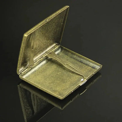 Vintage metal cigarette case with classic design, open view showing interior.