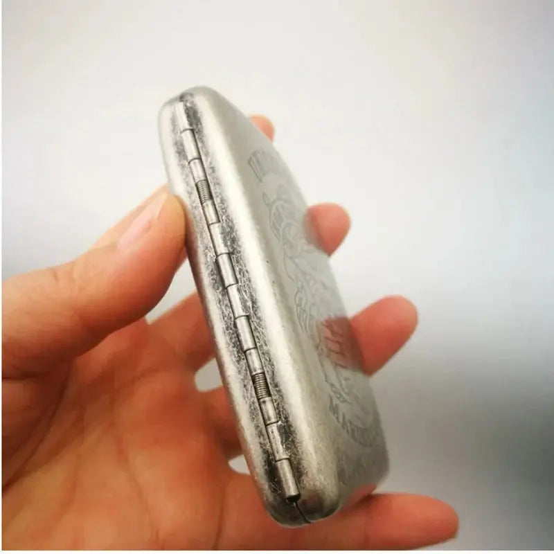 Vintage metal cigarette case with classic design, holds 20 cigarettes, shown in hand.