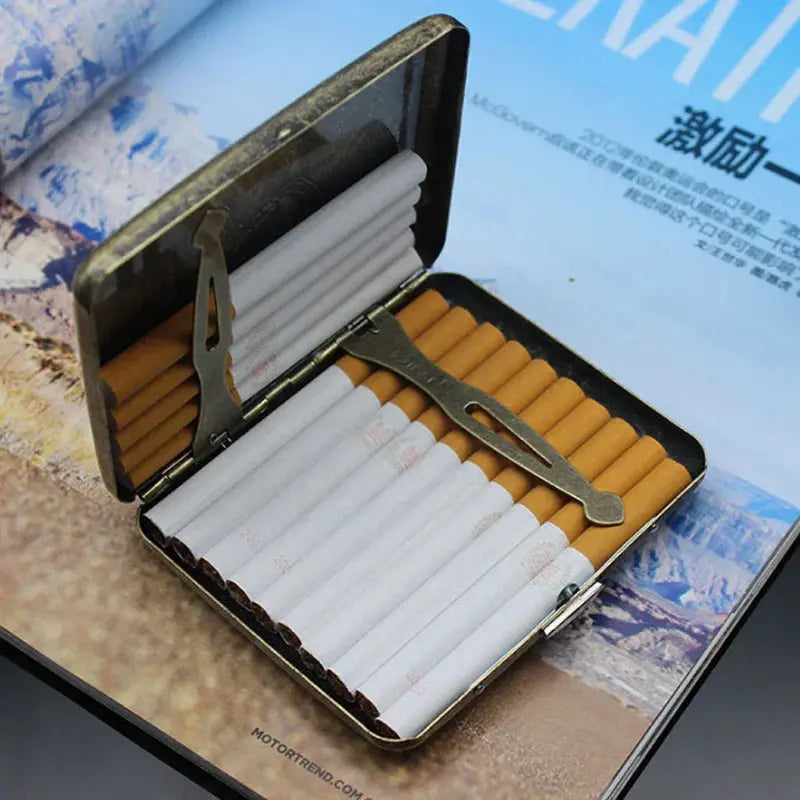 Vintage metal cigarette case with classic design, holding 20 cigarettes, displayed open on a magazine.