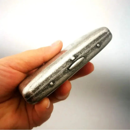 Vintage metal cigarette case in hand, classic design for 20 cigarettes.