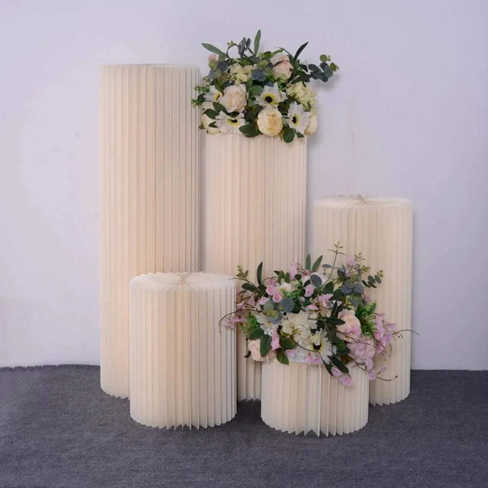 White paper folding cylinder decorations arranged in varying heights with floral accents for weddings and parties
