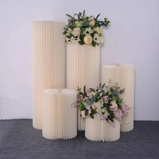 White paper folding cylinder decorations arranged in varying heights with floral accents for weddings and parties