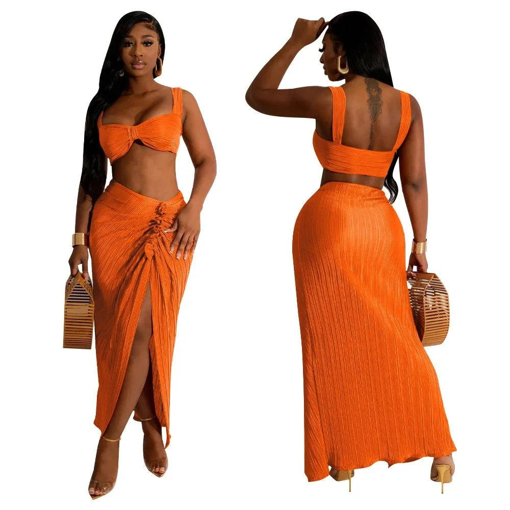 Summer two-piece set with backless halter top and high waist side slit pleated skirt in orange, beach style.