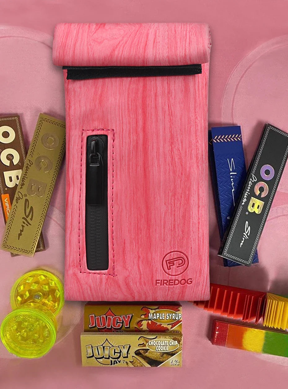 FIREDOG Smoking Smell Proof Pouch in pink PU leather with zipper and carbon lining, surrounded by smoking accessories.