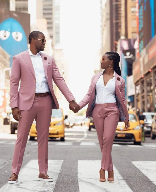 Couple wearing slim fit pink British suits holding hands on city street