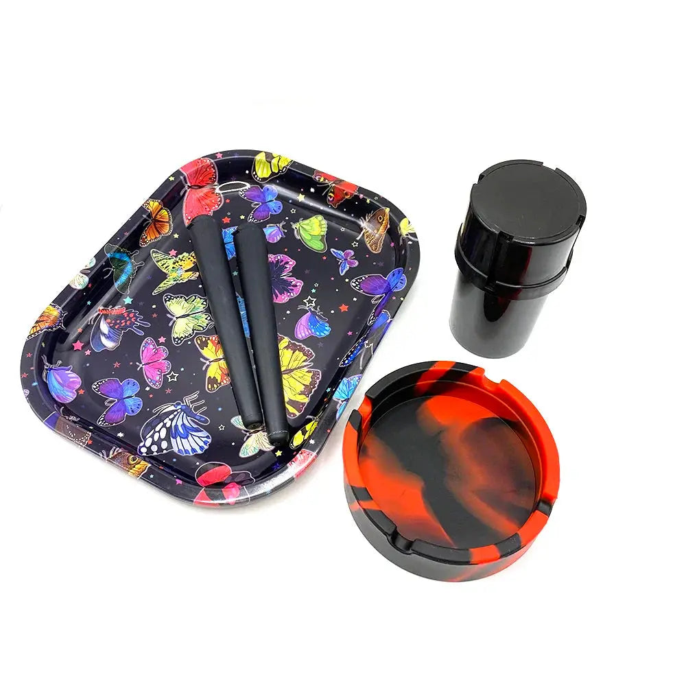 Cigarette plastic herb grinder set with colorful butterfly rolling tray, red and black silicone ashtray, and black storage container.