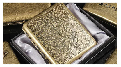 Retro brass cigarette box with intricate floral design in gift packaging.