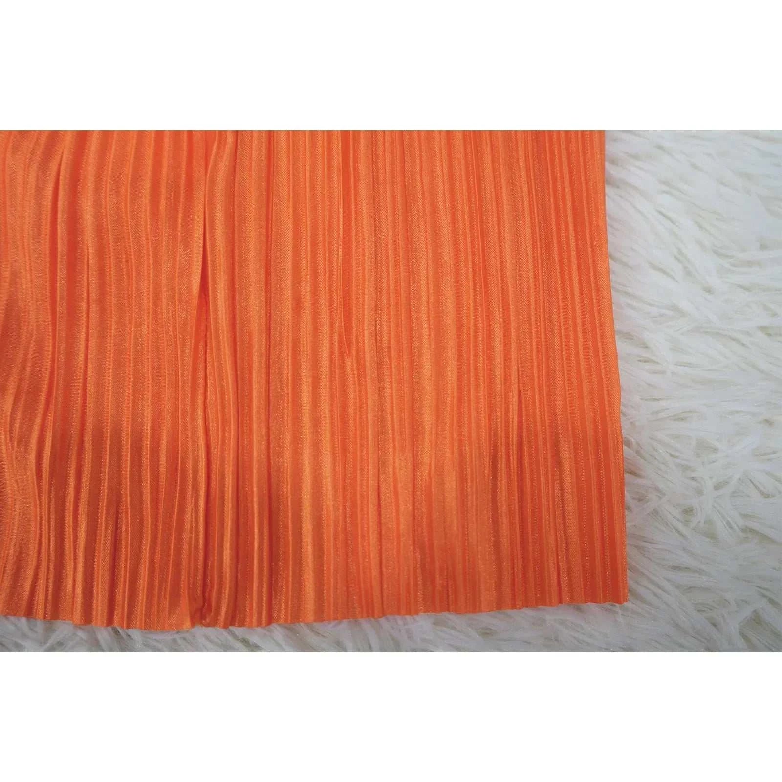 Orange high waist side slit pleated skirt on white fur background.