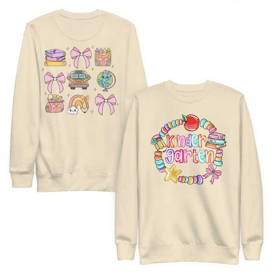 Unisex premium sweatshirt with colorful kindergarten-themed graphic designs on front and back, cream-colored, ribbed crew neck and cuffs, soft fleece interior.
