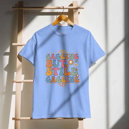 Saggin Still Gaggin DryBlend® T-Shirt hanging on a wooden ladder in sunlight.