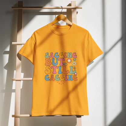 Saggin Still Gaggin DryBlend® T-Shirt with colorful lettering hanging on a wooden hanger.