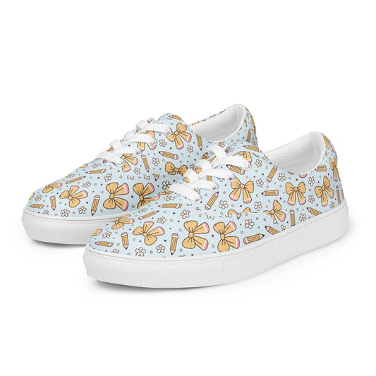 Women’s lace-up canvas shoes with a light blue background featuring bows, pencils, and small flowers design