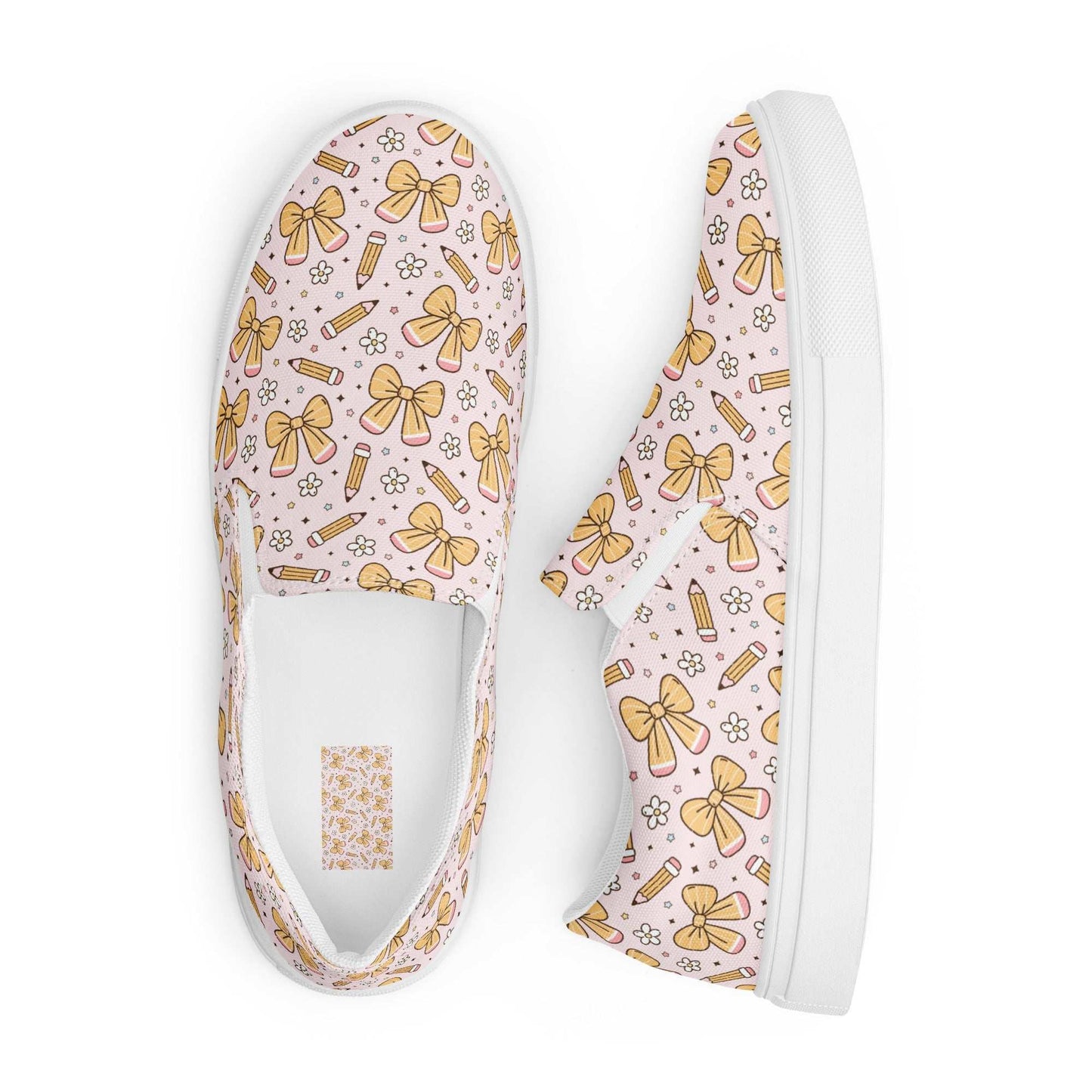 Women’s slip-on canvas shoes with pink background and yellow bow and pencil pattern, white rubber outsole, and elastic side accents for comfort
